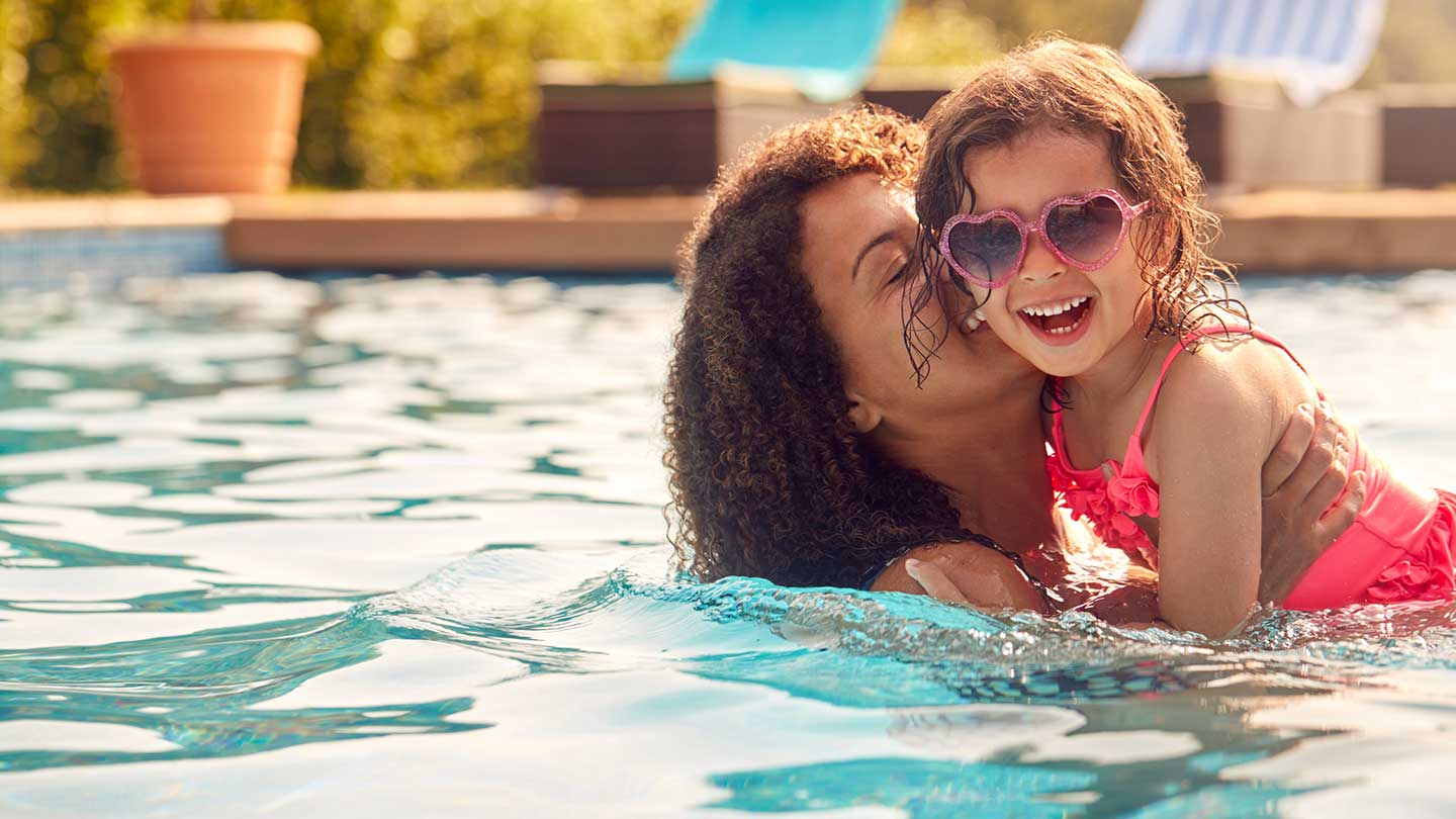 Mom holding her daughter in a pool
